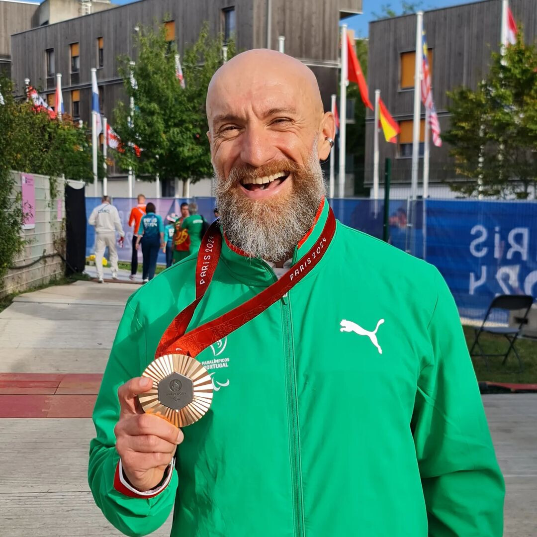 Paraciclista Luís Costa com um grande sorriso segurando a medalha de bronze na mão direita